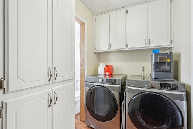 clothes washing area with washer and clothes dryer, cabinet space, and light wood finished floors