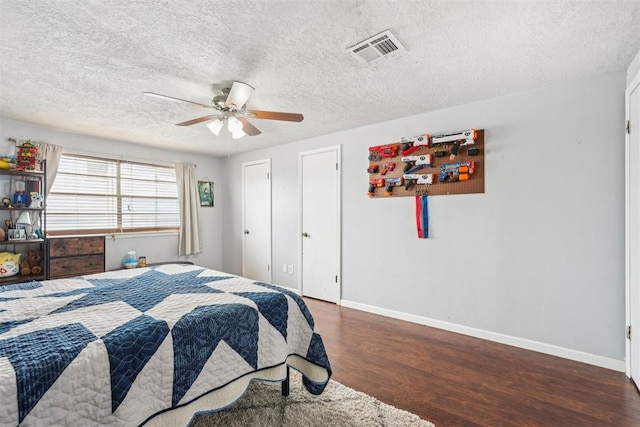 bedroom with visible vents, wood finished floors, baseboards, a textured ceiling, and a ceiling fan