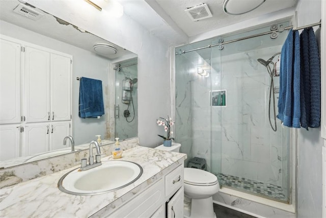 bathroom featuring visible vents, a marble finish shower, toilet, and vanity