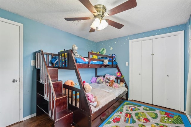bedroom featuring a closet, wood finished floors, baseboards, a textured ceiling, and a ceiling fan