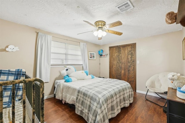 bedroom with a textured ceiling, a ceiling fan, baseboards, dark wood-type flooring, and visible vents