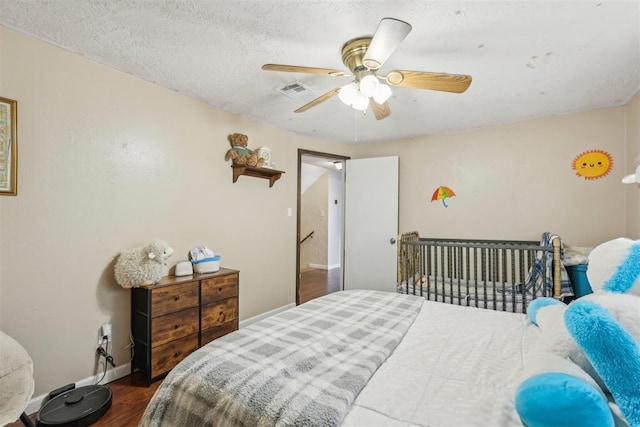 bedroom with baseboards, a ceiling fan, wood finished floors, and visible vents