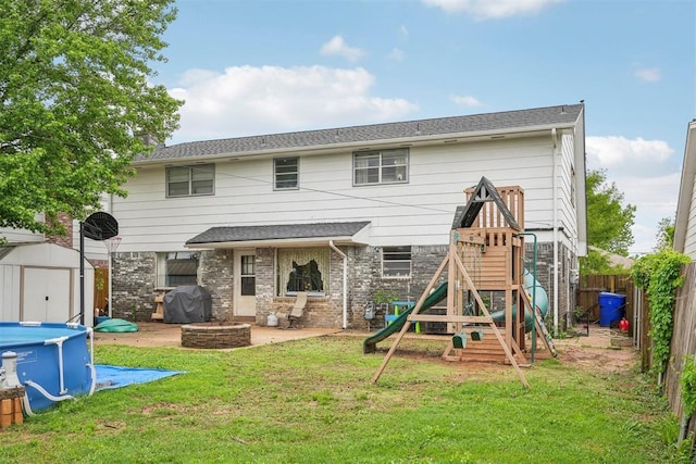 rear view of property with a storage unit, a fenced backyard, a playground, and a lawn