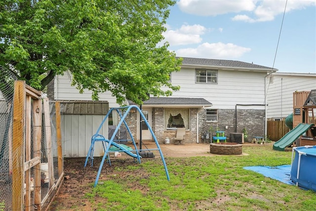 view of playground with a patio, a fenced backyard, a lawn, an outdoor fire pit, and central air condition unit