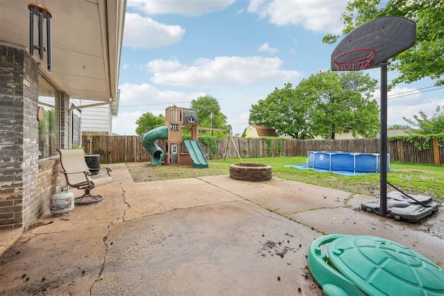 view of patio / terrace with a fenced backyard, a fenced in pool, a playground, and a fire pit