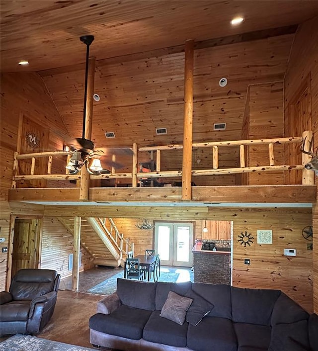 living area featuring wooden walls, high vaulted ceiling, french doors, wooden ceiling, and stairway