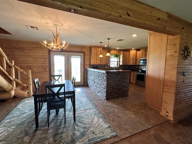 dining room featuring a textured ceiling, french doors, a chandelier, and visible vents