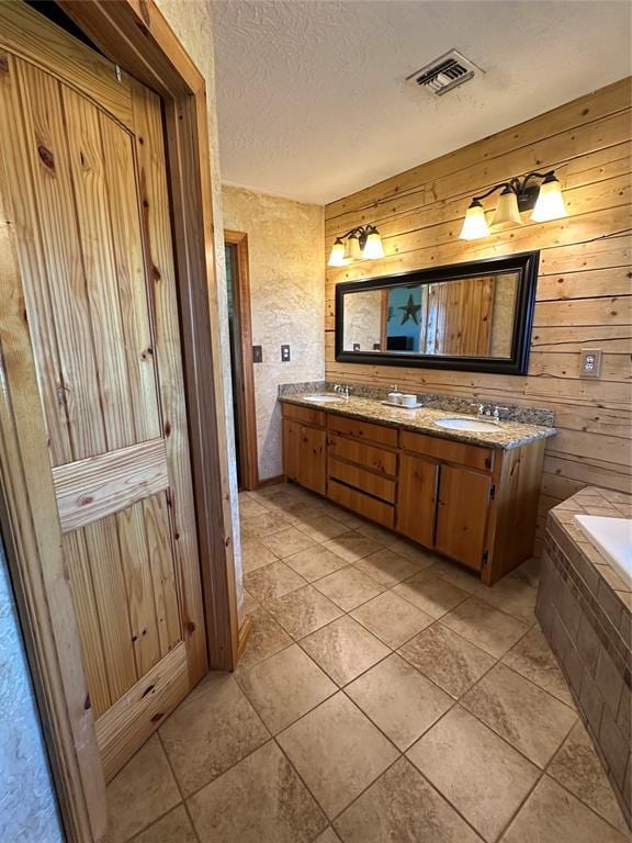 bathroom featuring wooden walls, a textured ceiling, visible vents, and a sink