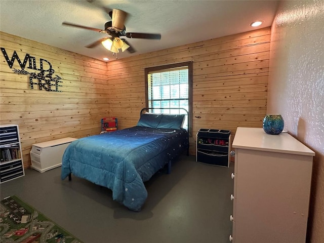 bedroom featuring wood walls, a ceiling fan, and concrete floors