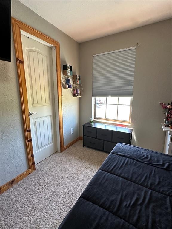 carpeted bedroom featuring baseboards and a textured wall