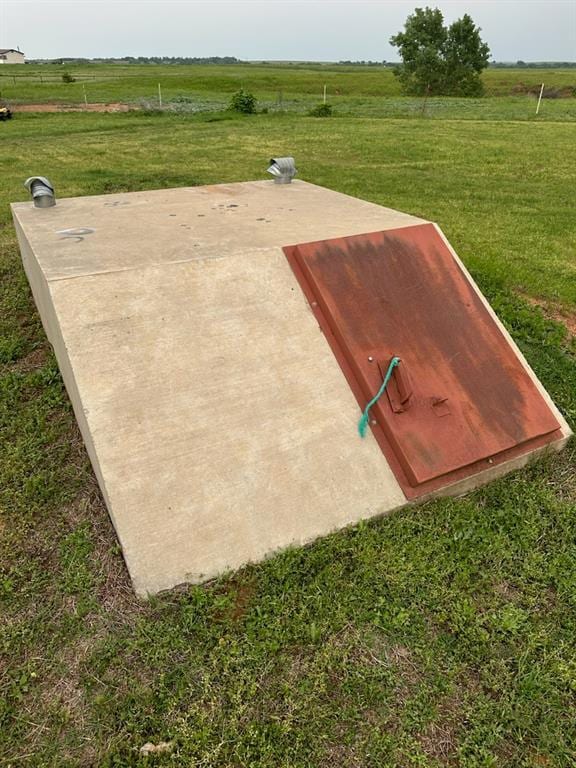 view of storm shelter featuring a lawn and a rural view