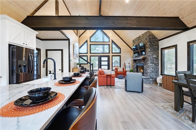 kitchen with light wood finished floors, wood ceiling, stainless steel fridge, white cabinetry, and beamed ceiling
