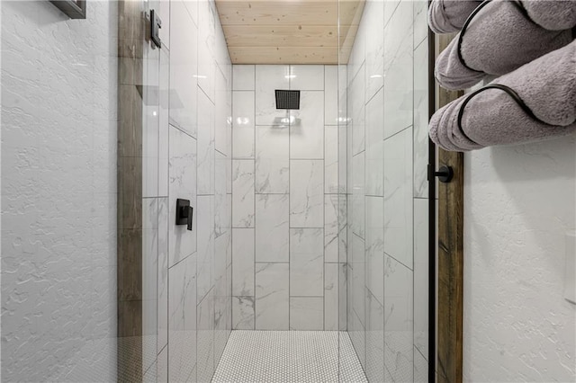 full bathroom featuring a stall shower, a textured wall, and wood ceiling