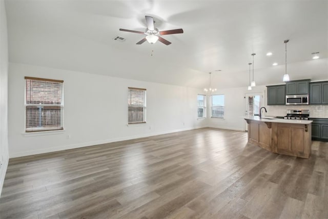 kitchen with visible vents, ceiling fan with notable chandelier, open floor plan, a sink, and appliances with stainless steel finishes