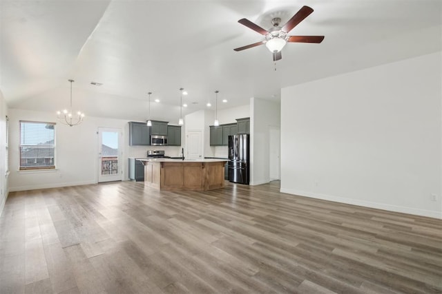 unfurnished living room featuring vaulted ceiling, baseboards, ceiling fan with notable chandelier, and wood finished floors