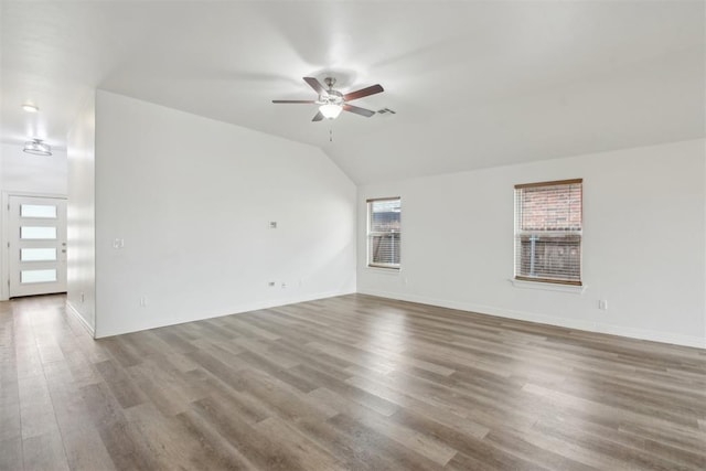 unfurnished living room featuring baseboards, ceiling fan, vaulted ceiling, and wood finished floors