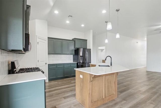 kitchen featuring visible vents, decorative backsplash, a sink, light wood finished floors, and appliances with stainless steel finishes
