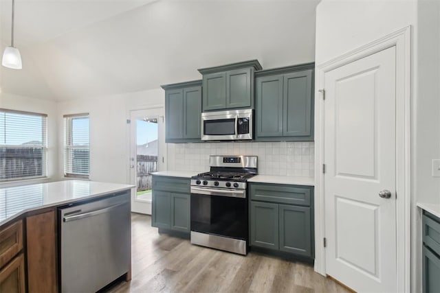 kitchen with light countertops, tasteful backsplash, light wood-style flooring, vaulted ceiling, and stainless steel appliances