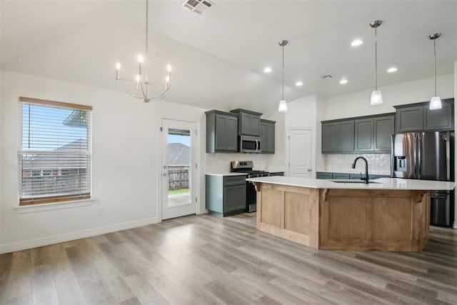 kitchen featuring appliances with stainless steel finishes, a sink, light countertops, a chandelier, and visible vents
