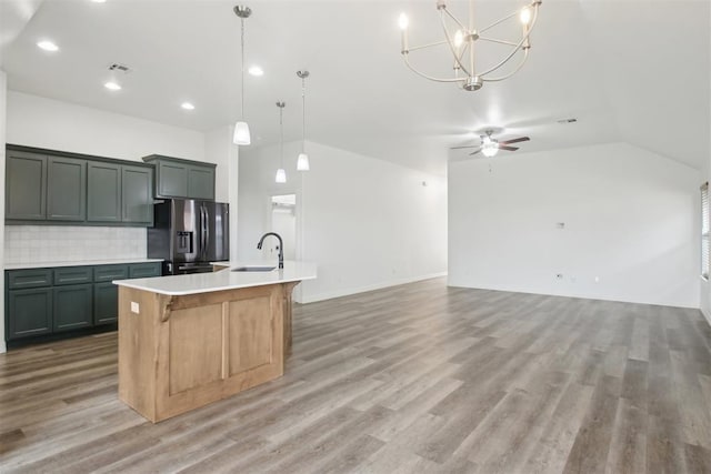 kitchen with decorative backsplash, light countertops, stainless steel fridge with ice dispenser, a sink, and vaulted ceiling