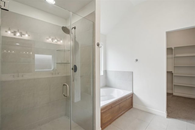 full bath featuring tile patterned flooring, baseboards, a shower stall, a spacious closet, and a garden tub