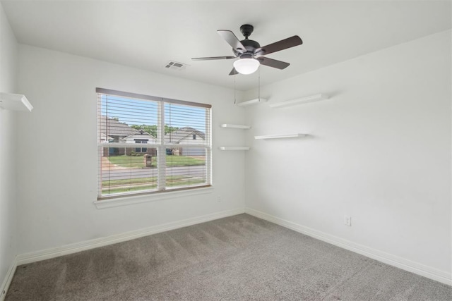 carpeted empty room with baseboards, a ceiling fan, and visible vents