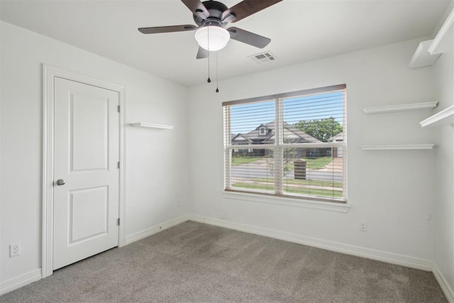 carpeted spare room with visible vents, a ceiling fan, and baseboards