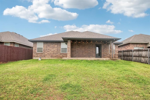 back of house featuring a fenced backyard, a lawn, and brick siding