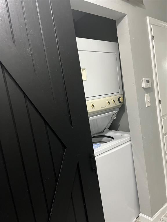 laundry room with laundry area, baseboards, and stacked washing maching and dryer