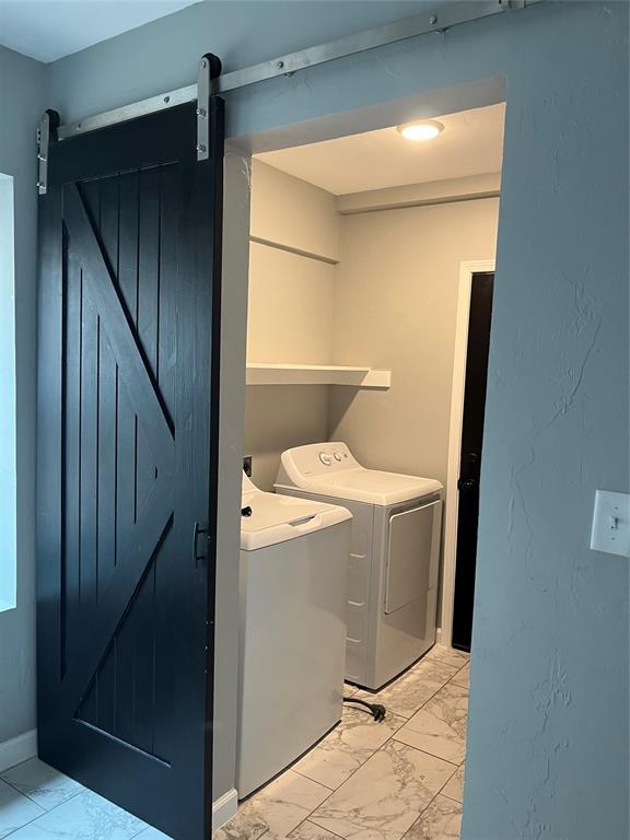 washroom with laundry area, marble finish floor, a barn door, and washer and dryer