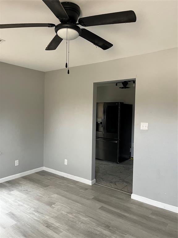 empty room featuring baseboards, ceiling fan, wood finished floors, and visible vents