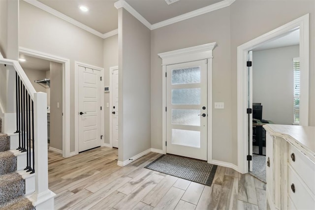 foyer featuring light wood-style floors, baseboards, crown molding, and stairs