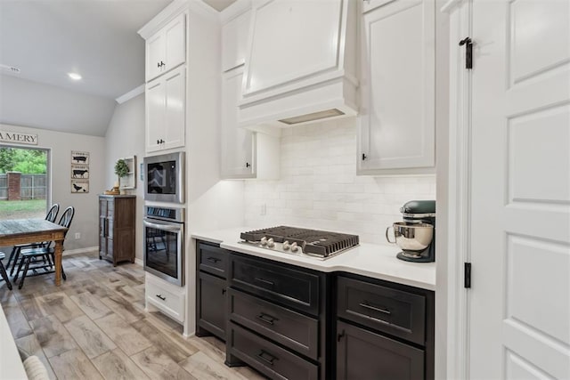 kitchen with white cabinets, appliances with stainless steel finishes, tasteful backsplash, and light countertops