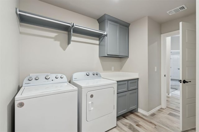 washroom with cabinet space, washer and dryer, light wood finished floors, baseboards, and visible vents
