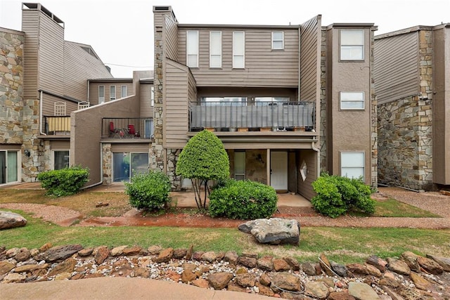 rear view of house featuring a balcony and stone siding