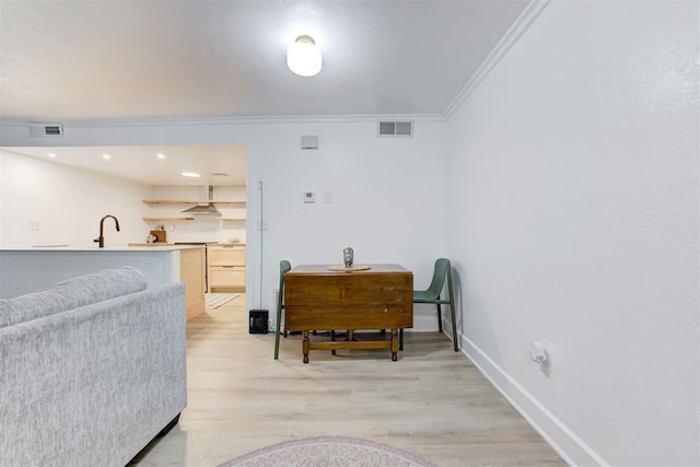 sitting room with crown molding, baseboards, light wood finished floors, and visible vents