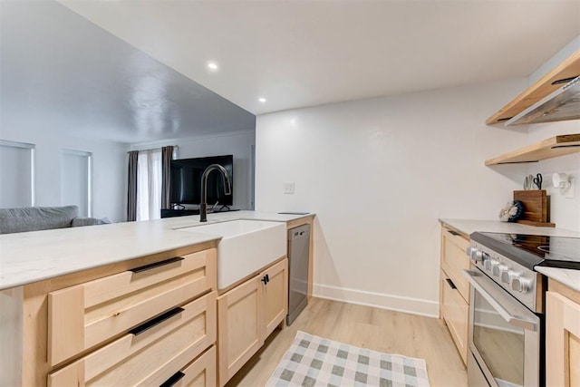 kitchen featuring appliances with stainless steel finishes, light countertops, a sink, open floor plan, and light wood-style floors