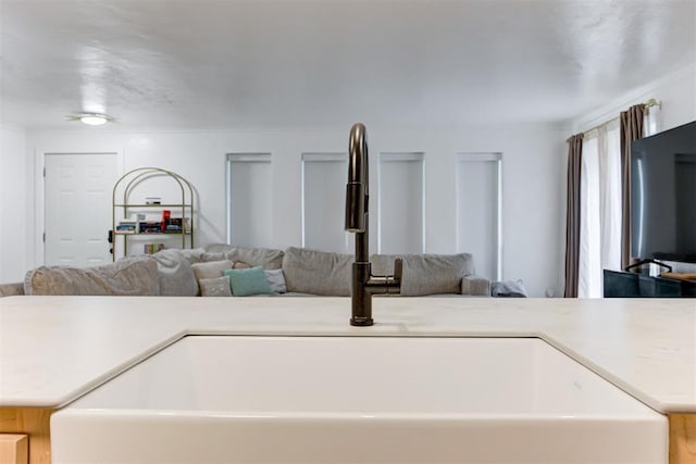 kitchen with a sink, light countertops, ornamental molding, and open floor plan