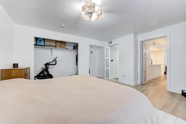 bedroom featuring baseboards, a closet, wood finished floors, and visible vents