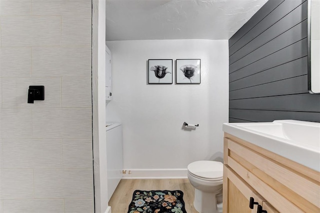 bathroom with baseboards, vanity, toilet, and wood finished floors
