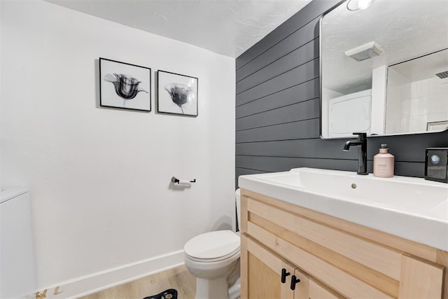 bathroom featuring baseboards, wood finished floors, toilet, and vanity
