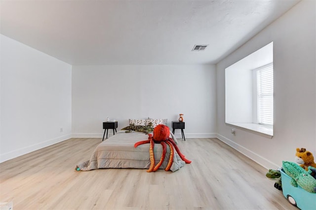 bedroom featuring baseboards, wood finished floors, and visible vents