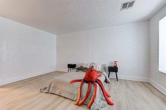 bedroom with baseboards, visible vents, and wood finished floors