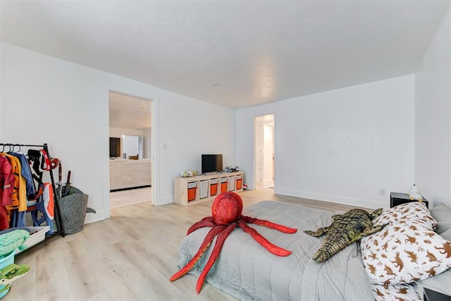 bedroom featuring baseboards, connected bathroom, and wood finished floors