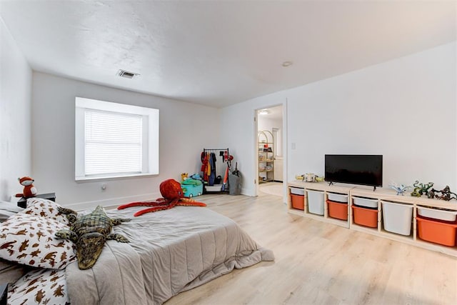 bedroom with baseboards, visible vents, and wood finished floors