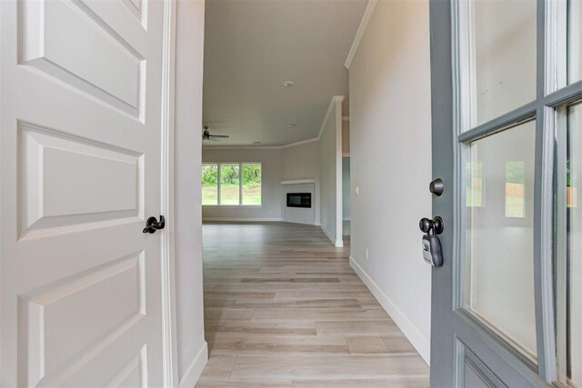 corridor featuring crown molding, light wood-style floors, and baseboards