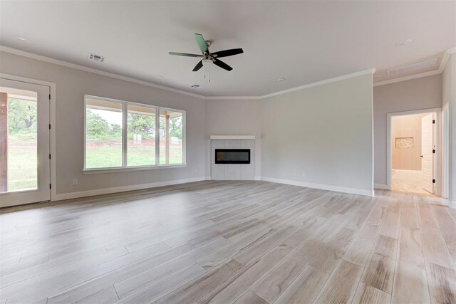 unfurnished living room with crown molding, light wood-style floors, a ceiling fan, baseboards, and visible vents