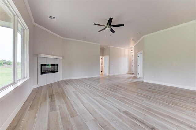 unfurnished living room with ceiling fan, baseboards, light wood-type flooring, a tile fireplace, and visible vents