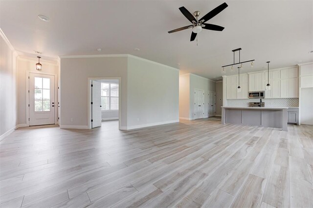 unfurnished living room with baseboards, ornamental molding, light wood-style flooring, and a ceiling fan