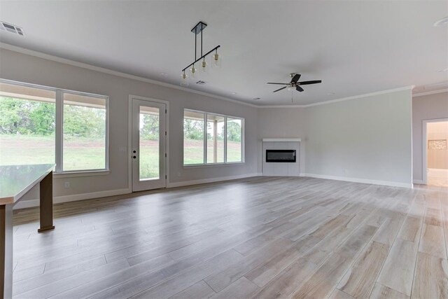 unfurnished living room featuring visible vents, ornamental molding, baseboards, a ceiling fan, and light wood-style flooring